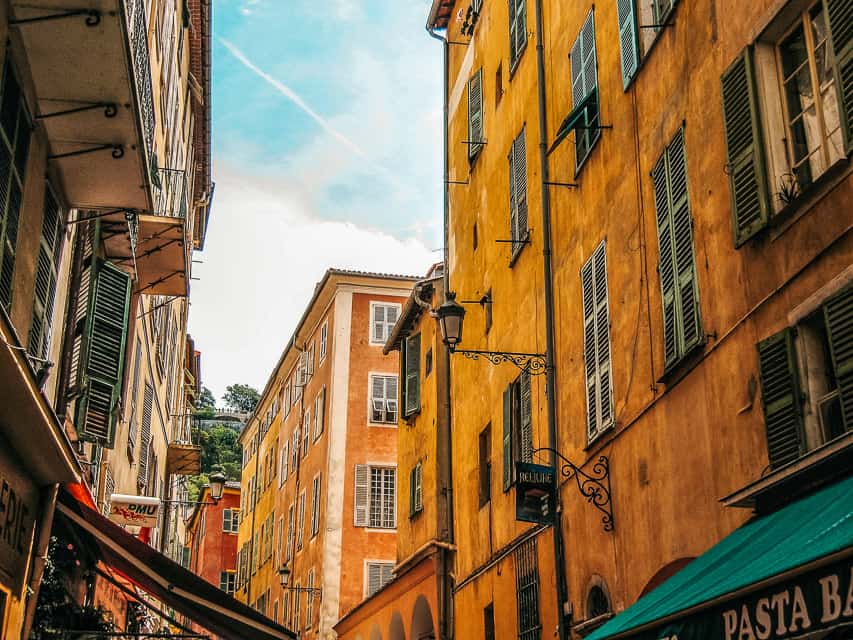 The tight streets of Old Town, with the golden buildings and green shutters. The view is of the upper parts of the buildings - a good spot to consider when deciding where to stay in Nice. 