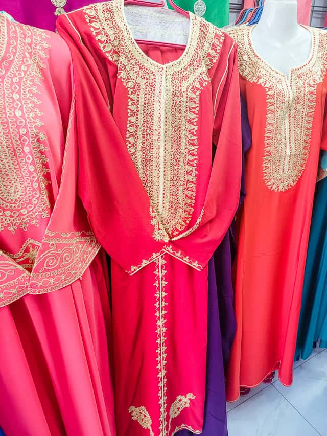 3 kaftans on mannequins in a shop in Morocco. These kaftans have embroidery around the neckline. 