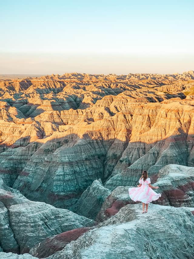 Sunrise at Big Badlands Overlook. A woman in a pink and white dress watches the light strike the badlands.