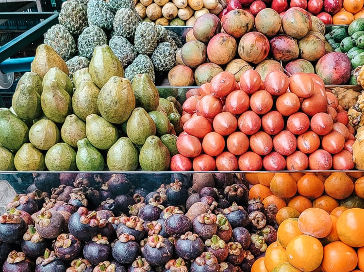 A display of tropical fruits for sale in Colombia. Guava, mango, and mangosteen are some of the fruits displayed.