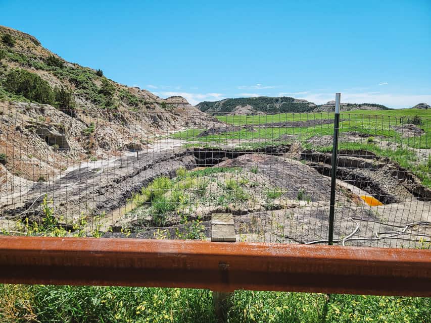 A fence blocks access to a circular ditch filled with orange water. The site of an underground coal fire.