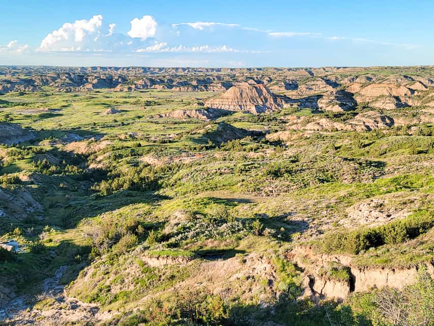 One of the most accessible viewpoints of Theodore Roosevelt National Park is Painted Canyon Overlook. Brightly colored hills catch the light of the setting sun.