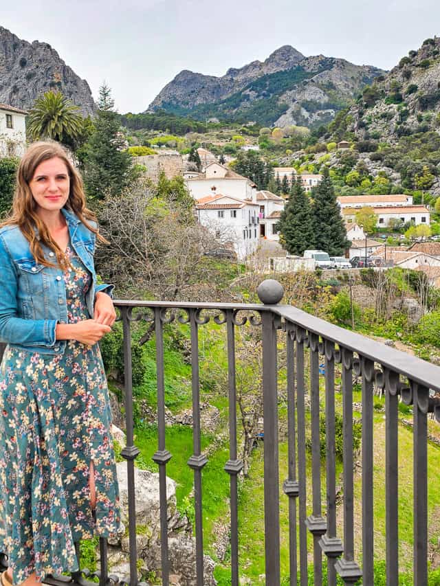 A woman smiles at the camear, as it looks back at the village and mountains at the Mirador de los Asomaderos - the viewpoints are one of the best things to do in Grazalema. 
