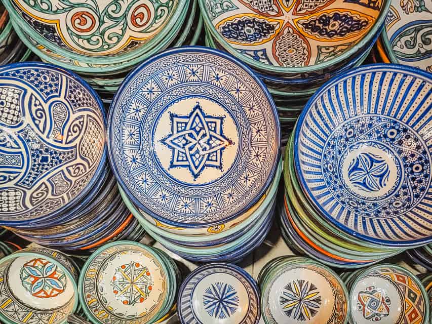 Stacks of painted ceramic bowls in varying sizes, painted with intricate designs. Ceramics are one of the best souvenirs to buy in Morocco. 