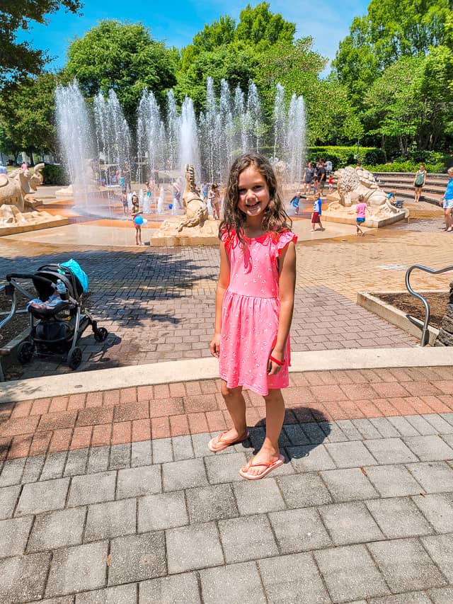 A girl in a pink dress enjoys a splash pad at Coolidge Park in Chattanooga.