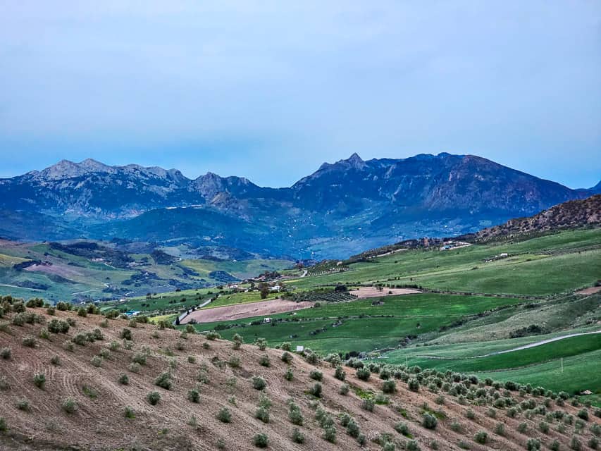 Mountains rise in the distance with rolling Spanish hills In the foreground.
