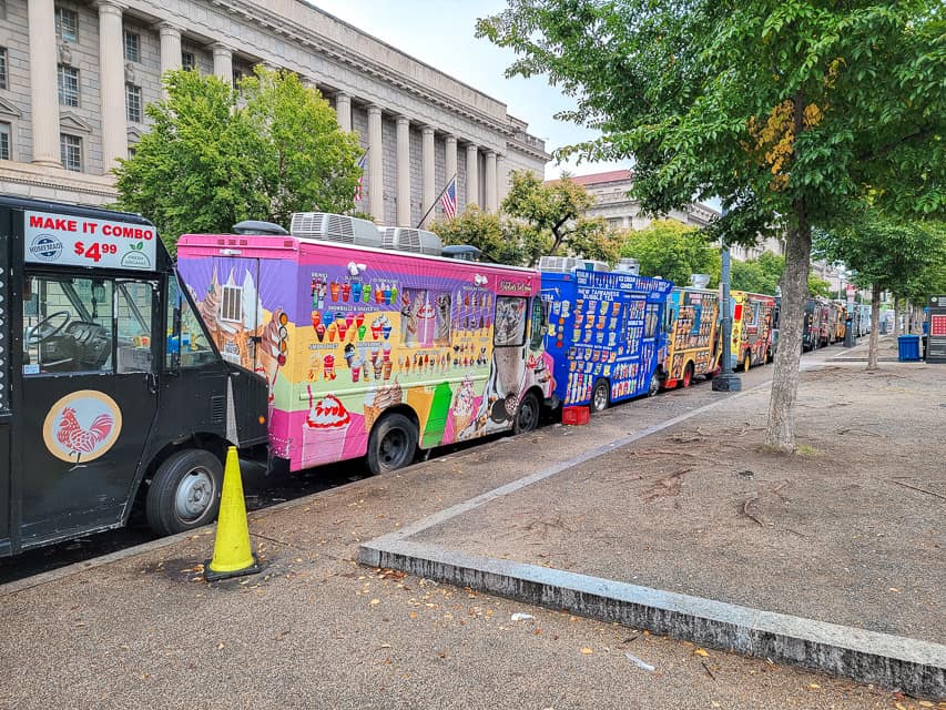 A row or colorful food trucks line the curb near the National Mall in Washington, DC. 