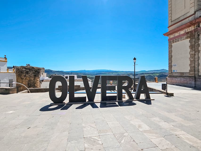 Sign that says Olvera in black lettering. Taking a photo here is a popular thing to do in Olvera, Spain.